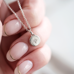 Silver necklace with a star pendant held by a hand against a blurred background