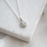 Silver necklace with a round pendant on a light fabric background